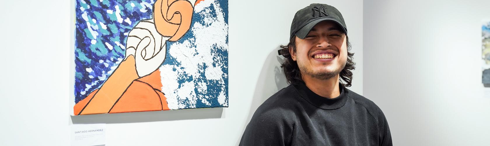 student posing with his painting